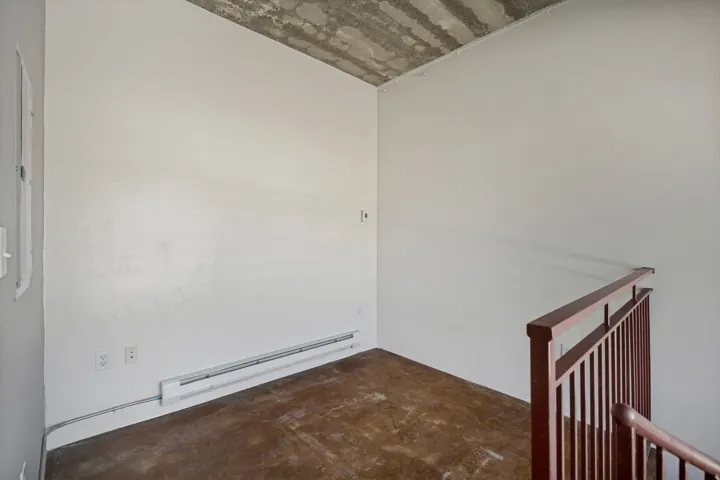 Exposed concrete ceiling, white painted walls, and wood-finish flooring