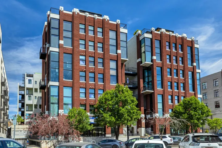 Brick exterior featuring extensive window lines, multiple balconies, and a flat roofline