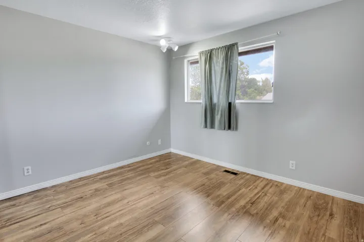 Wood-finish flooring with white trim, light gray painted walls, and two windows