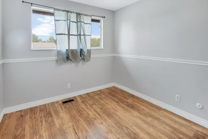 Wood-finish flooring, light gray walls, white trim, and a prominent window