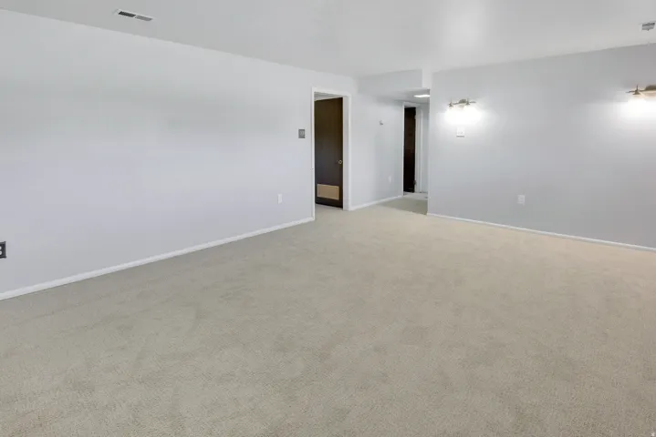 Neutral-toned carpeting, light-colored walls, and two wall-mounted light fixtures