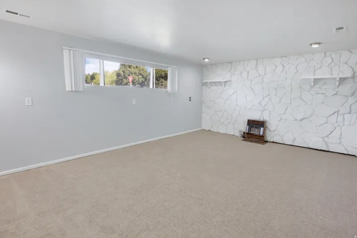 Carpeted room featuring a white textured accent wall, recessed lighting, and built-in shelving