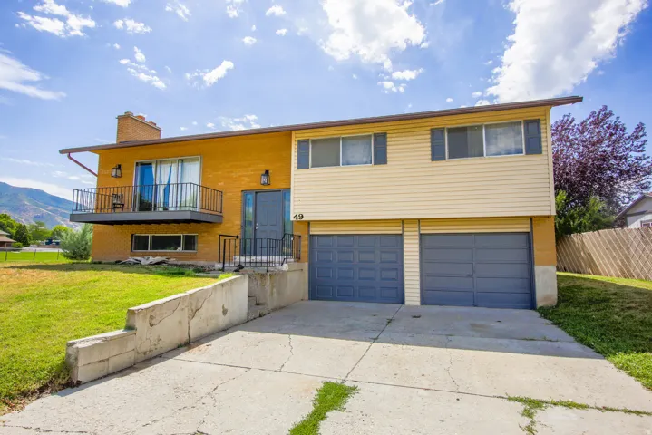 Split-level exterior featuring brick and siding, a front-facing balcony with metal railings, and a two-car garage with individual doors