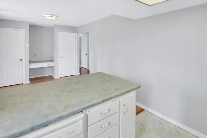 Kitchen island with integrated dishwasher, light-toned countertop, and white cabinetry
