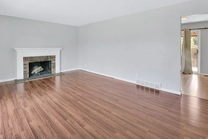 Brick fireplace with white mantel, wood-finish flooring, and sliding glass door