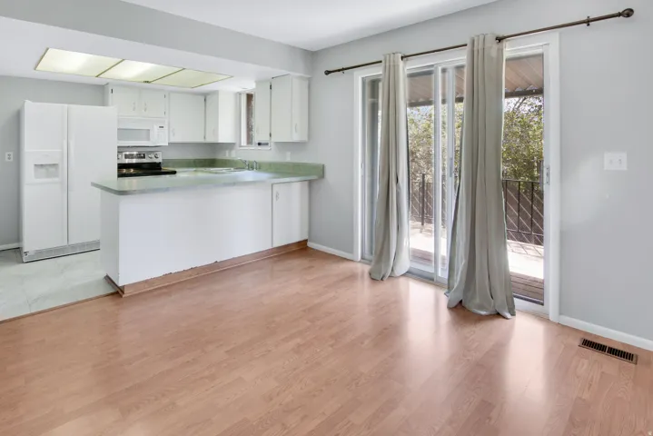 Wood-finish flooring, white cabinetry, light countertops, and a sliding glass door