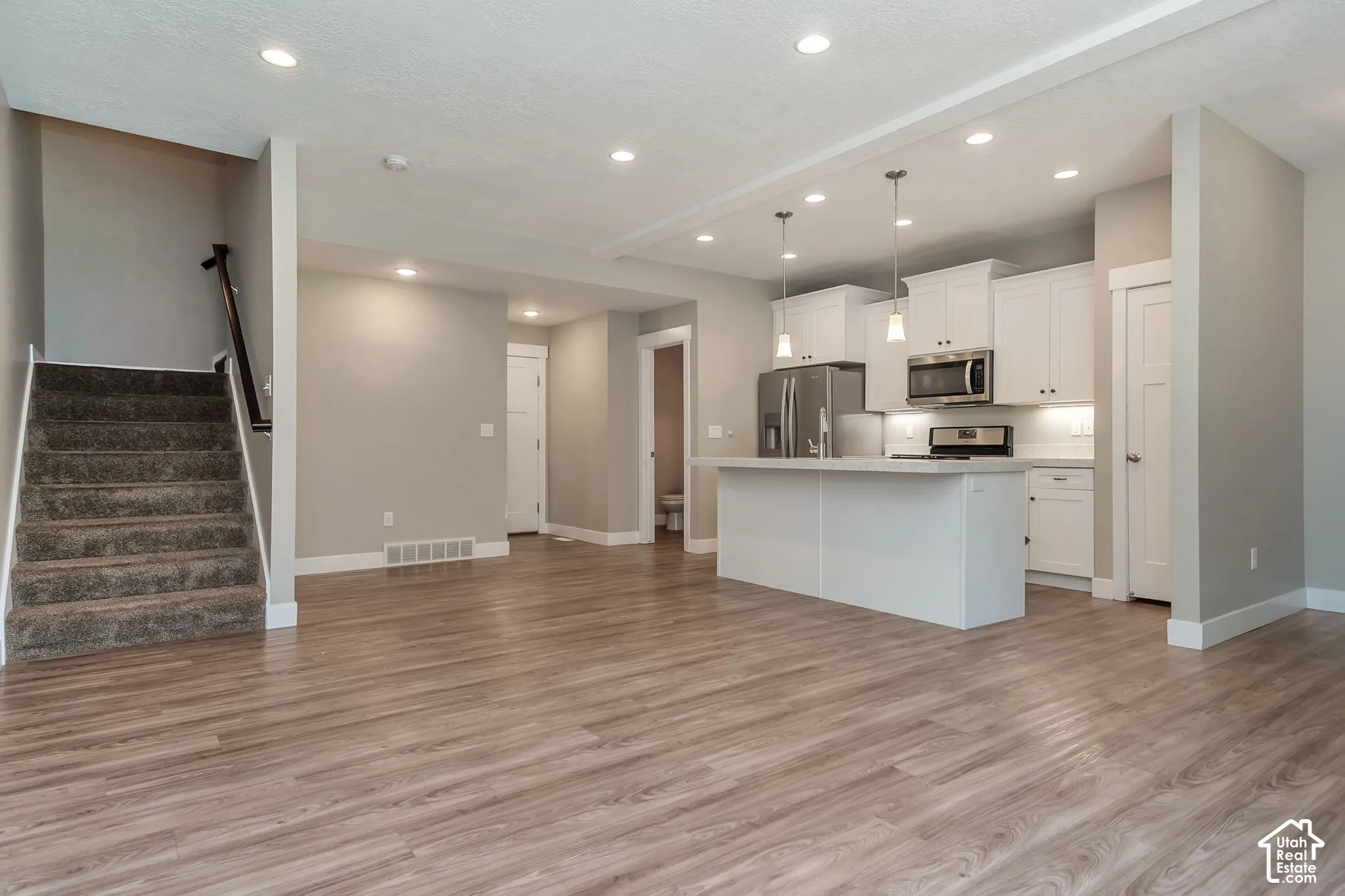 Open-concept living area featuring wood-finish flooring, recessed lighting, and a modern kitchen