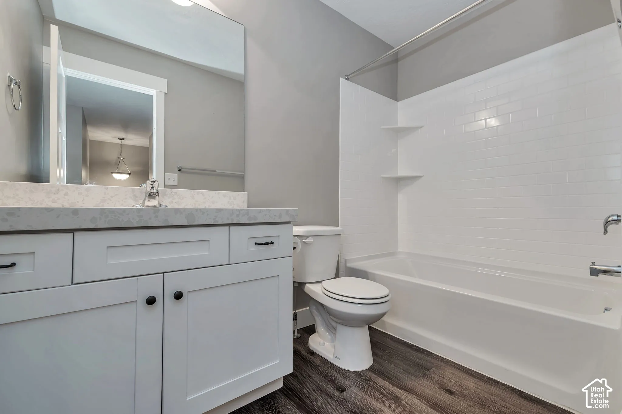 White shaker cabinetry with dark hardware, a light-colored countertop, and a built-in mirror