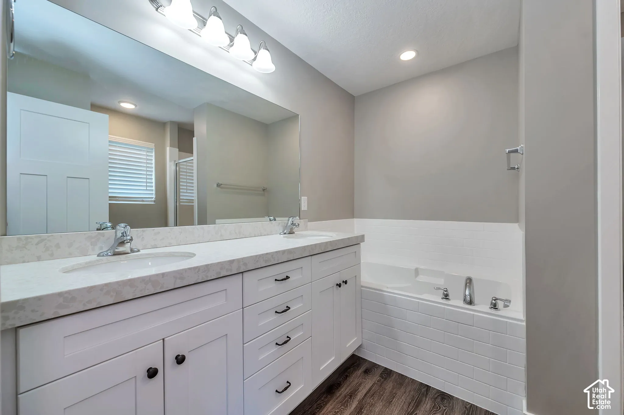 Dual vanity with undermount sinks, stone-finish countertop, and white shaker-style cabinetry