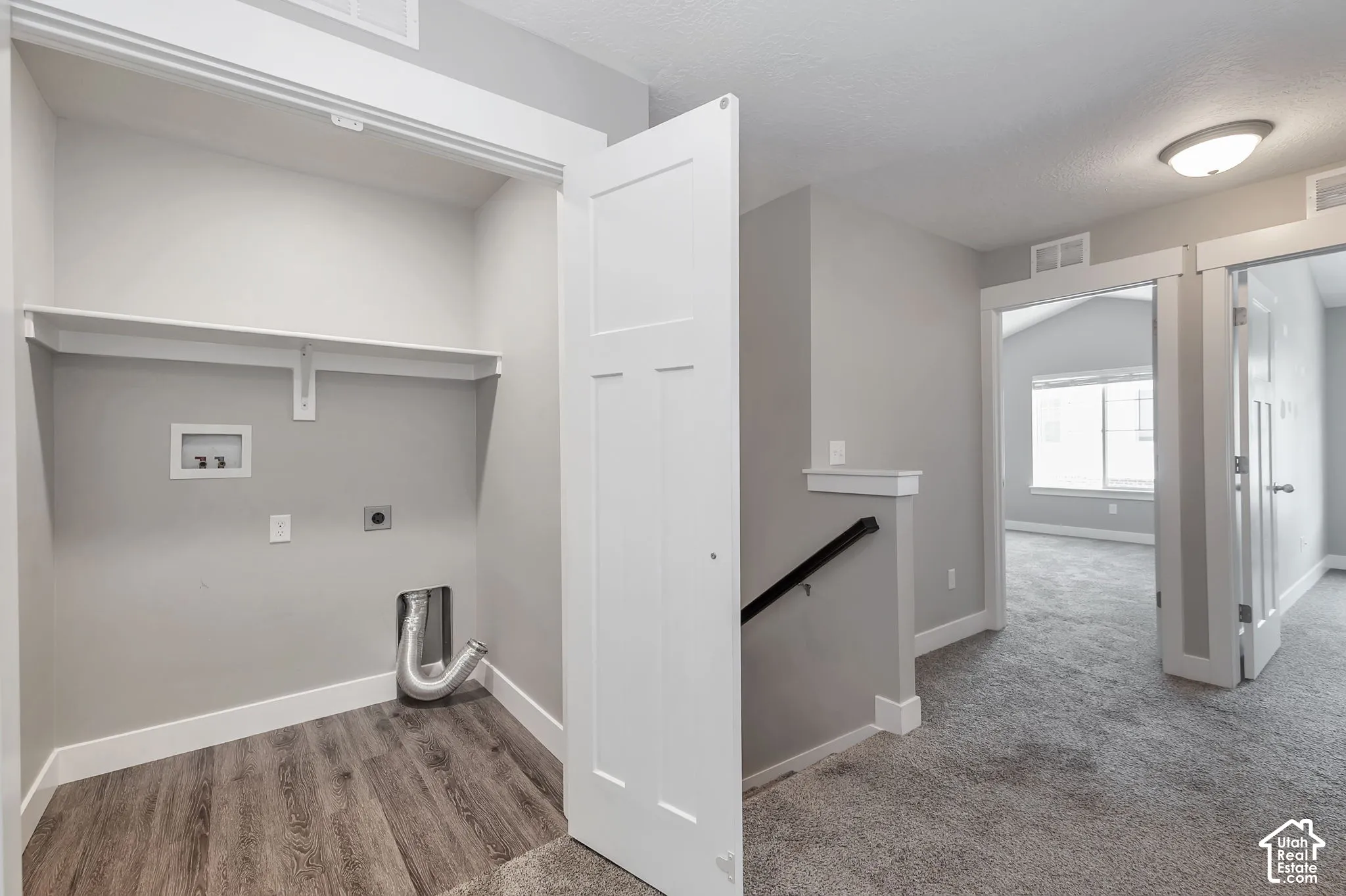 Laundry area with wood-finish flooring and integrated shelving