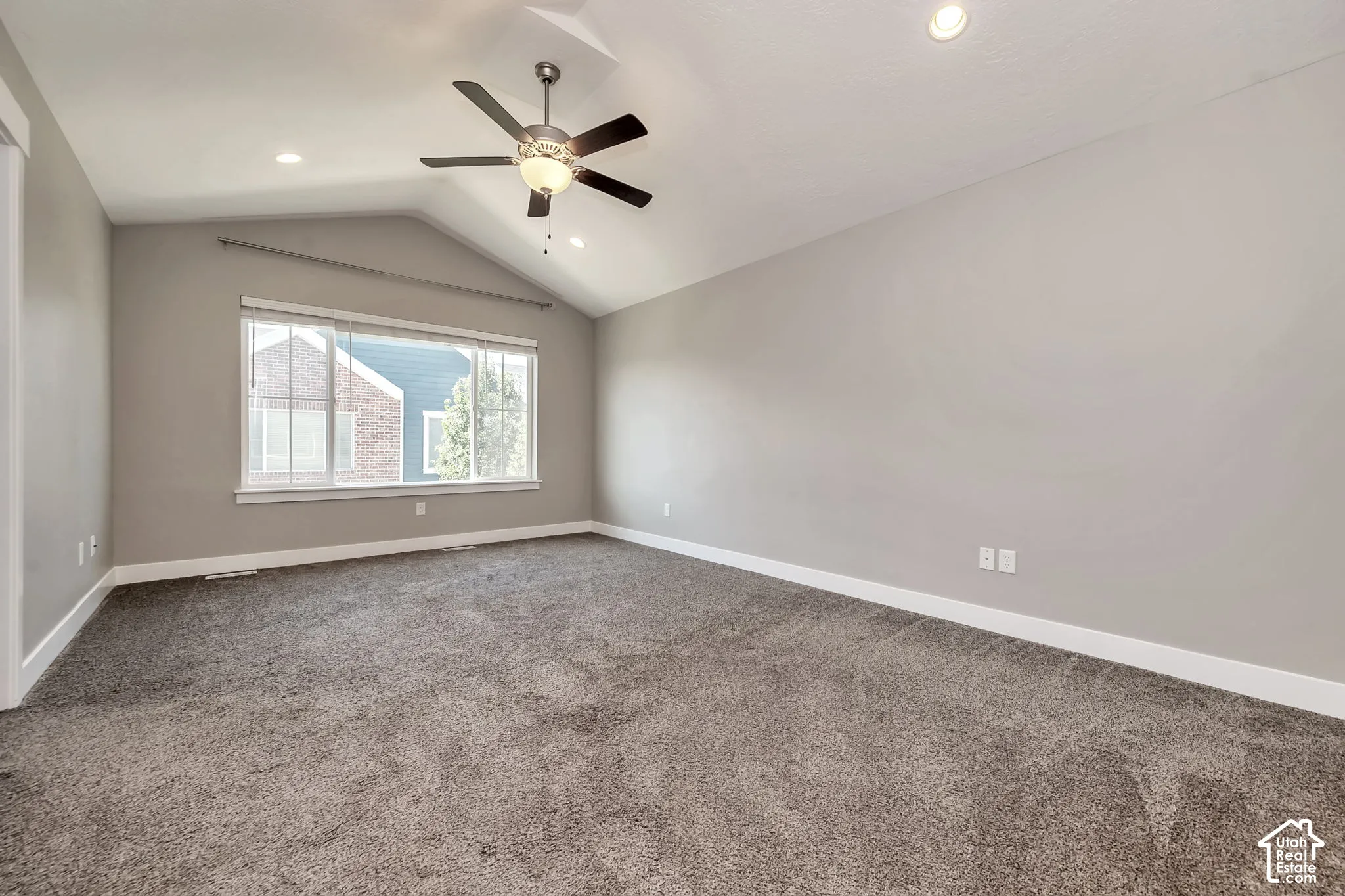 Vaulted ceiling, ceiling fan with integrated lighting, recessed lighting, large window with blinds, and neutral tone carpeting