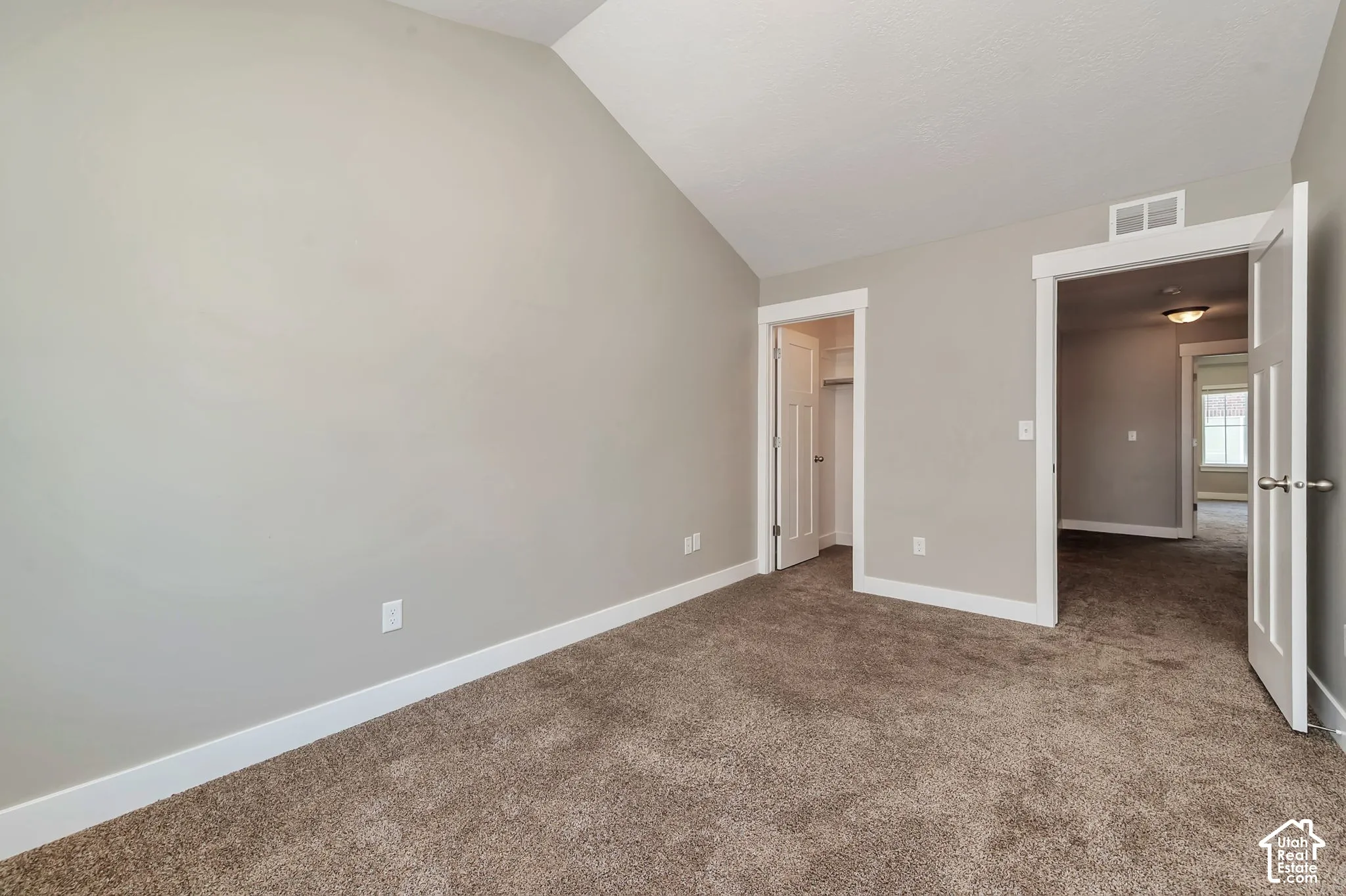 Vaulted ceiling, neutral wall paint, plush carpet, white trim, and white doors
