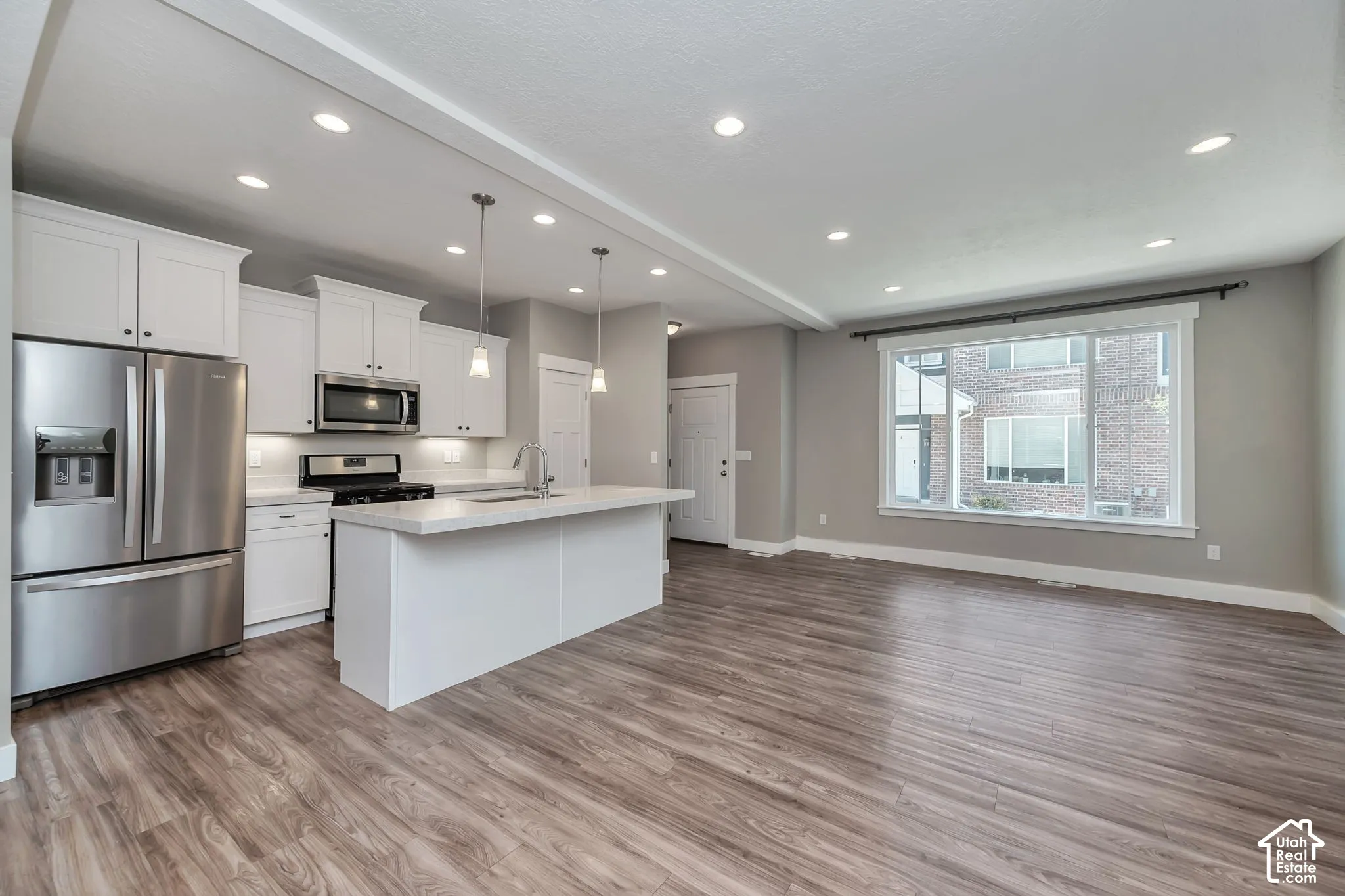 Open-concept living area featuring wood-finish flooring, recessed lighting, and a kitchen with white cabinetry