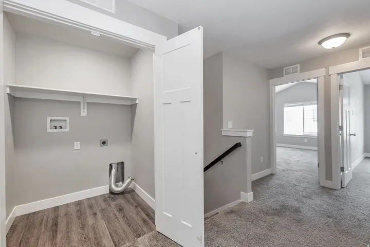 Laundry area with wood-finish flooring and integrated shelving