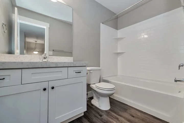 White shaker cabinetry with dark hardware, a light-colored countertop, and a built-in mirror