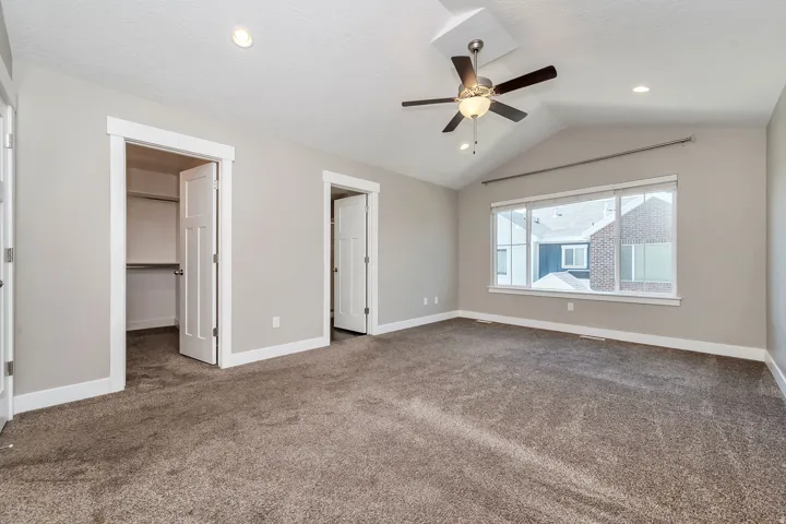 Vaulted ceiling with a ceiling fan, recessed lighting, carpeted flooring, and a large window
