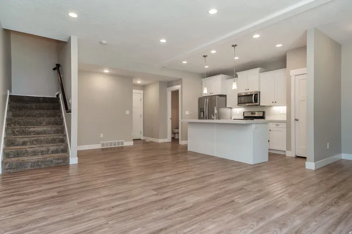 Open-concept living area featuring wood-finish flooring, recessed lighting, and a modern kitchen