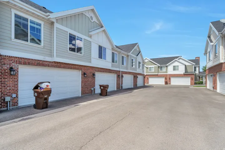 Two-story townhome exteriors featuring brick and siding finishes, individual garage doors, and ample paved driveway space