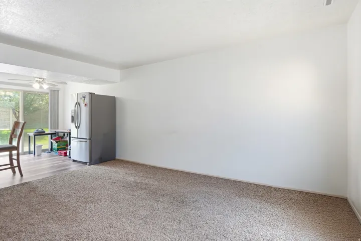 Stainless steel refrigerator with freezer drawer, wood-finish flooring, glass sliding door, and ceiling fan with light fixture