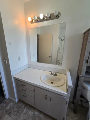 Vanity with an integrated sink, dual-handle faucet, and overhead lighting fixture