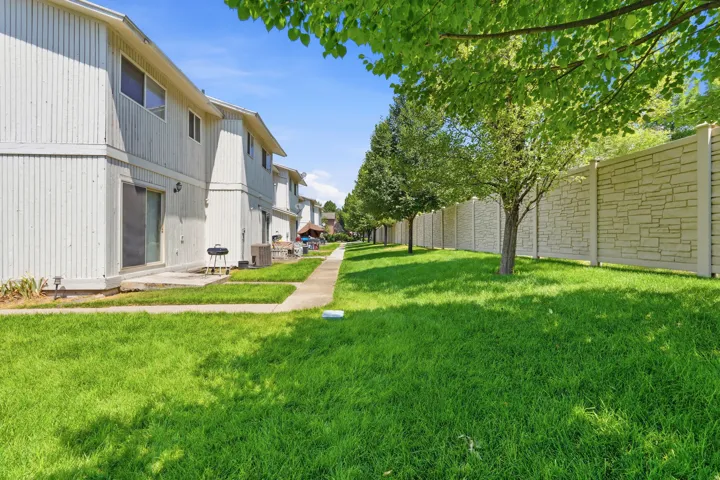 Expansive green lawn with mature trees and a decorative privacy fence