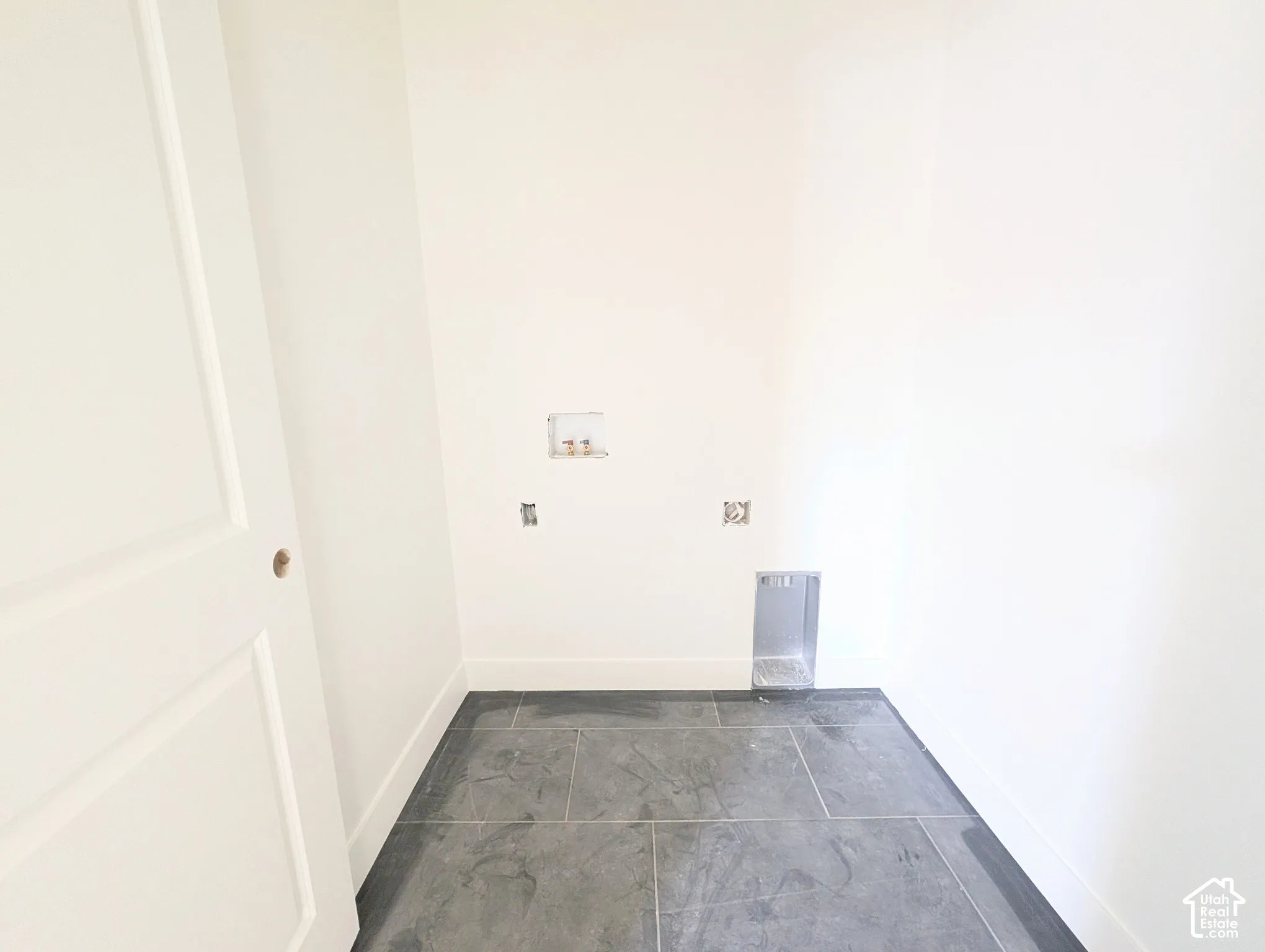 Dark gray tile flooring with white baseboards and white walls