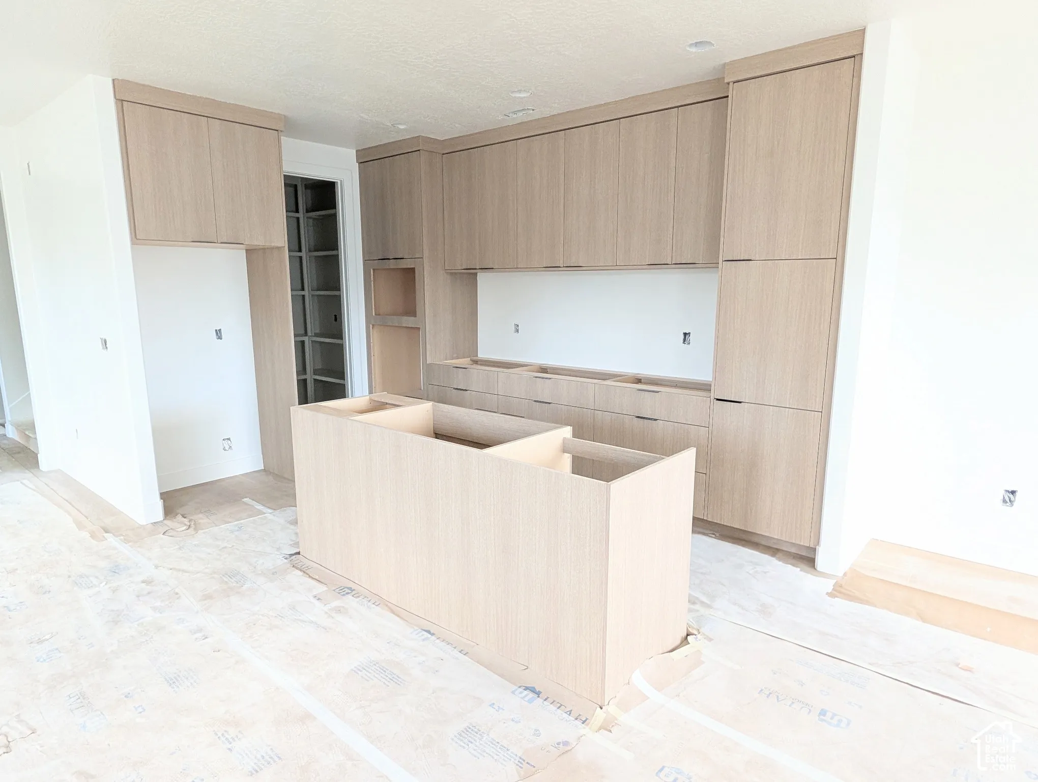 Extensive natural wood-finish cabinetry, central island base, and a built-in pantry with glass-paneled doors