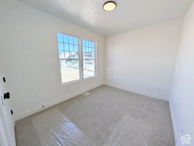Bright, light-filled bedroom featuring dual French doors with gridded panes, neutral wall finishes, and neutral carpeting