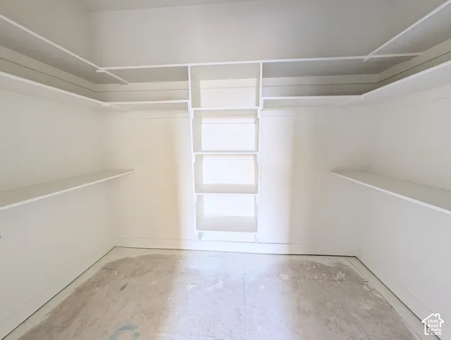 Walk-in closet featuring extensive built-in shelving and hanging rods