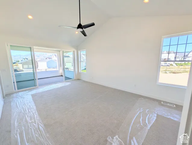 Vaulted ceiling with recessed lighting and a ceiling fan, sliding glass doors to an outdoor patio, and carpeted flooring