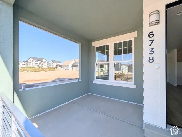 Covered concrete porch with a window, contemporary address numbers, and an exterior light fixture