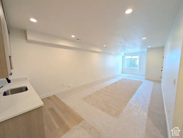 Recessed lighting with wood-finish cabinetry, a white countertop, and an undermount sink