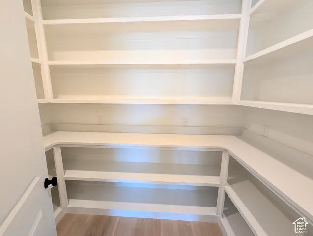 Built-in shelving with multiple storage levels, lower countertop space, wood-finish flooring, and a white paneled door with a black hardware knob