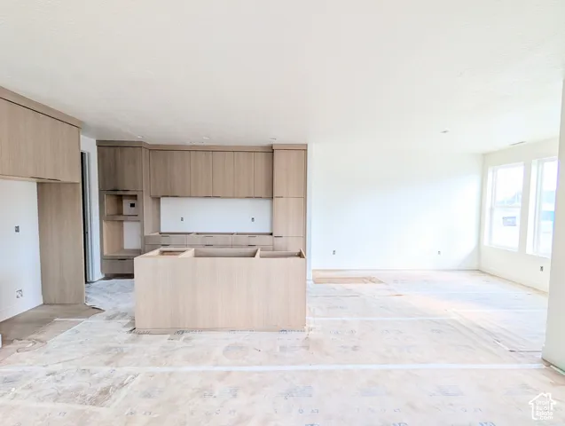 Open-concept layout with recessed lighting, light wood-finish cabinetry, and an integrated kitchen island
