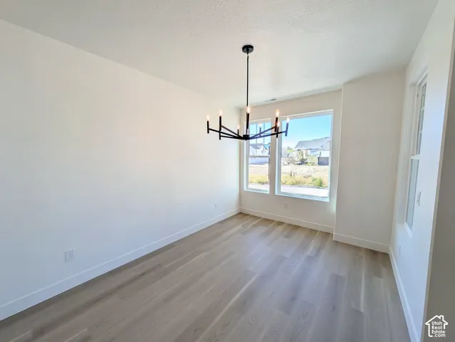 Spacious room with wood-finish flooring, multiple windows, and a contemporary chandelier