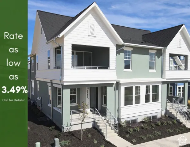 Green-hued exterior facade with white trim, featuring a covered balcony with a metal railing