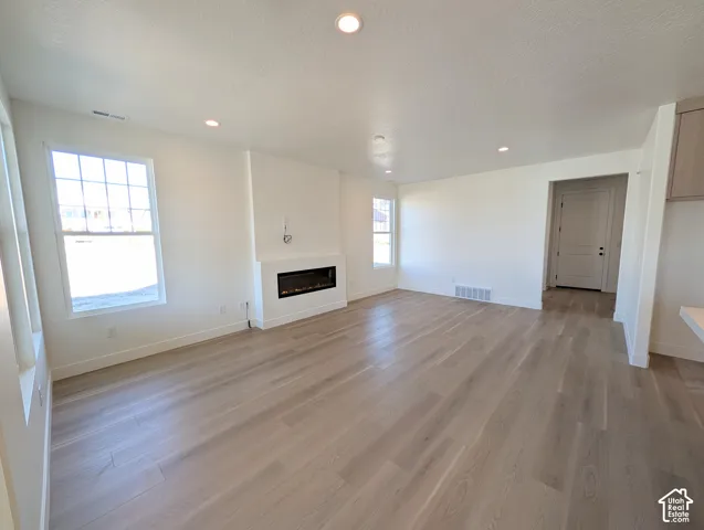 Recessed lighting, wood-finish flooring, white walls, multiple windows, and a built-in linear fireplace