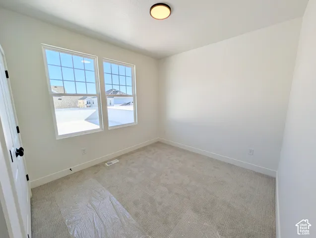 Bright secondary bedroom with dual casement windows offering natural light, neutral carpeting, and clean white walls