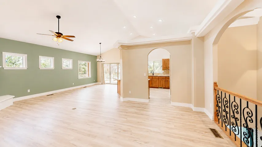 Vaulted ceiling, recessed lighting, wood-finish flooring, ceiling fan, and arched entryway