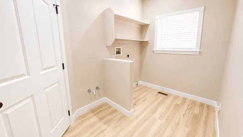 Laundry area with wood-finish flooring and built-in shelving