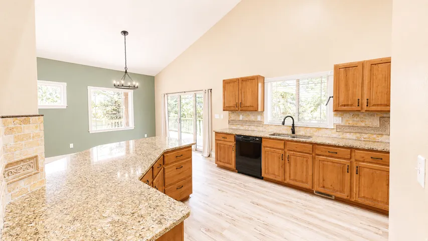 Kitchen with wood-finish cabinetry, granite countertops, and a tile backsplash