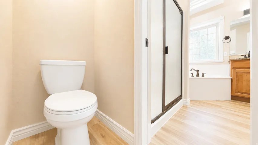 Private commode alcove with light wood-finish flooring