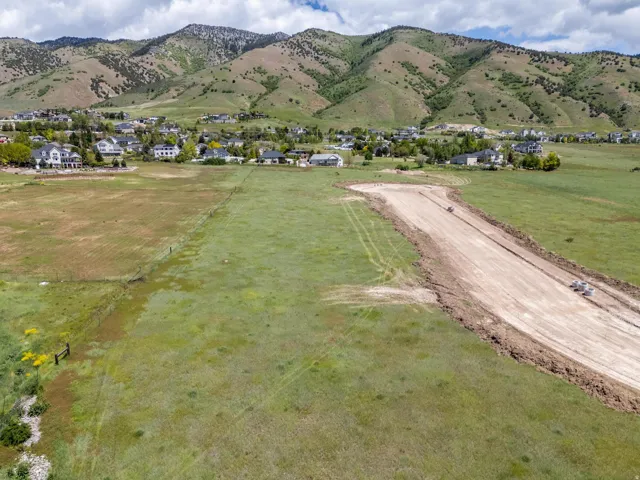 Expansive land parcel featuring prepared roadbed and surrounding green acreage