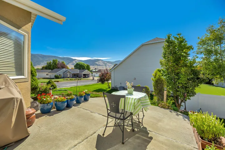 Concrete patio with a white privacy fence and established trees