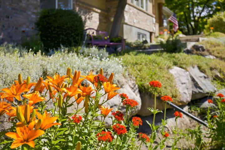 Lush landscaping featuring various flowering plants, natural rock formations, and a terraced garden design