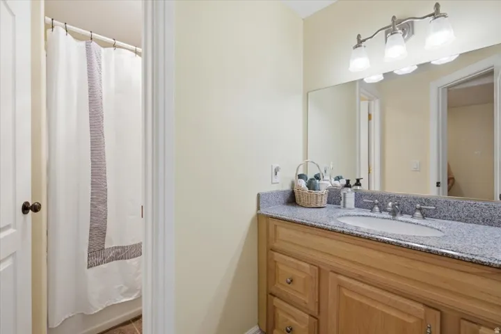 Wood-finish vanity with an integrated sink, granite-style countertop, and a three-light vanity fixture