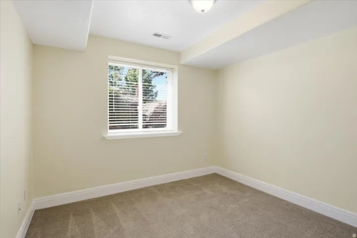 Light-colored walls, carpeted flooring, and a single window with blinds