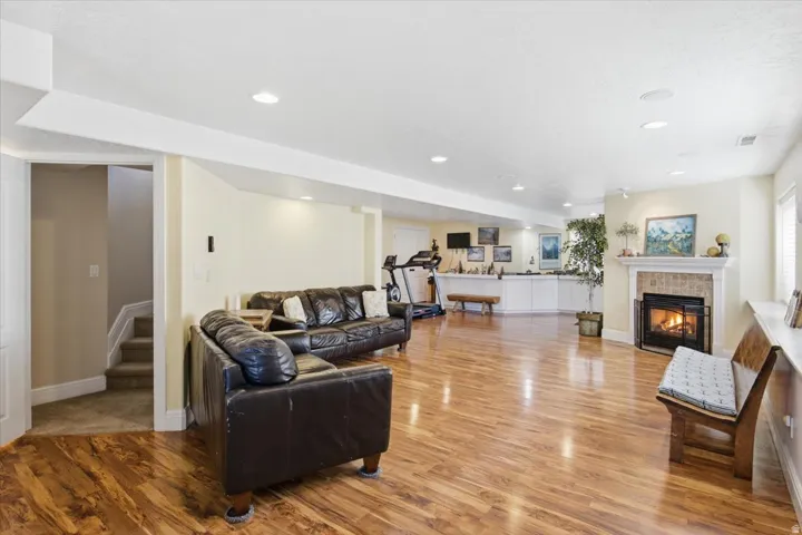 Expansive living area with wood-finish flooring, recessed lighting, a fireplace with a tile surround, and built-in cabinetry