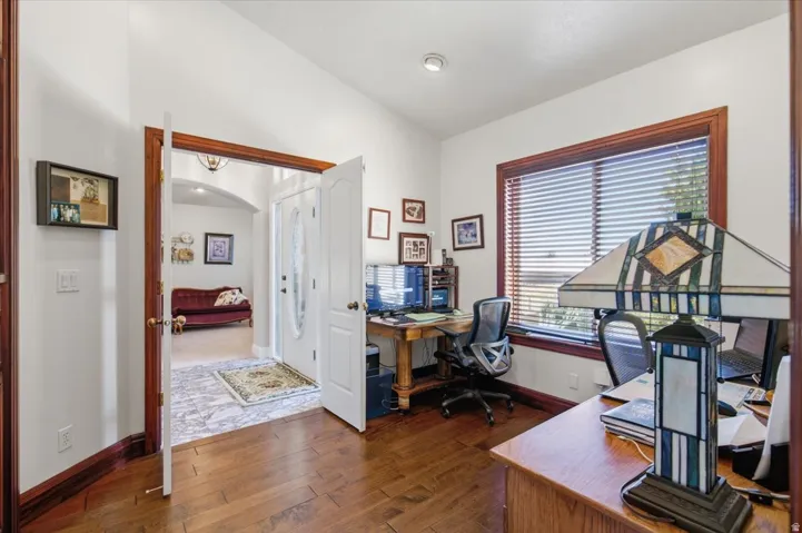 Wood-finish flooring with dark wood trim, white walls, and a window with blinds