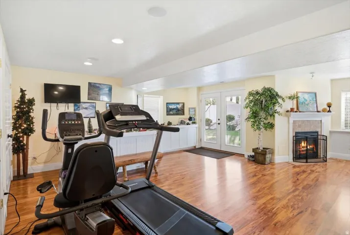 Spacious room featuring wood-finish flooring, recessed lighting, and a corner fireplace with a tiled surround